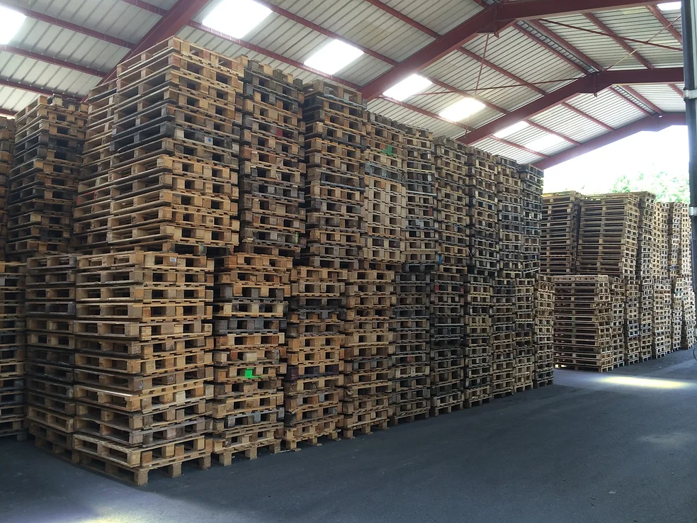 Vue intérieure de notre entrepôt de Châteauneuf (73) avec des piles de palettes en bois revalorisée.